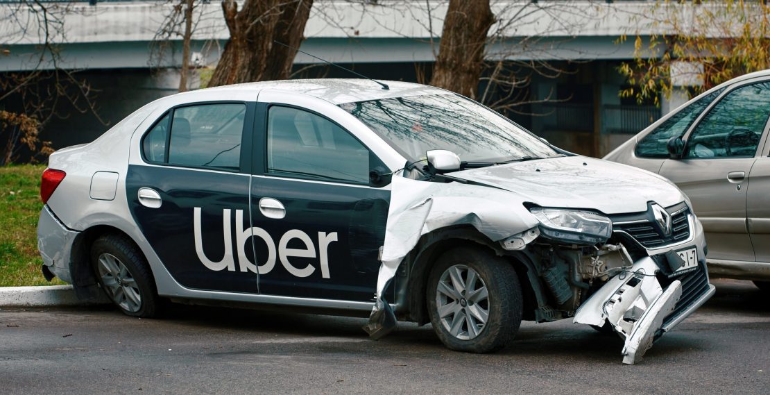 Minsk, Belarus - Nov 2019. Damaged car of Uber taxi service at the parked zone after car accident on the road.  Wrecked taxi car after a head-on collision in a parking lot
